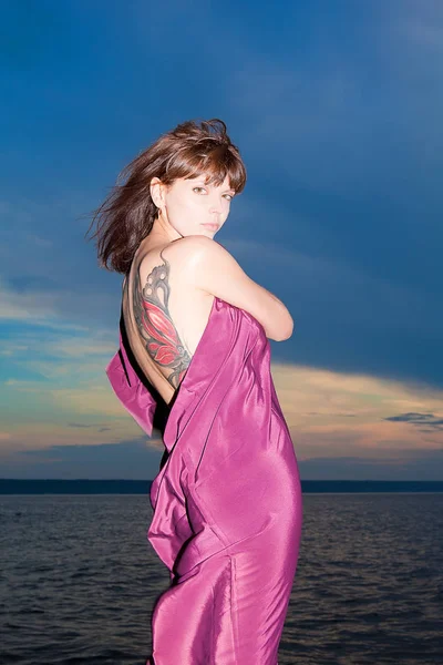 Woman in open dress with butterfly tattoo on her back — Stock Photo, Image