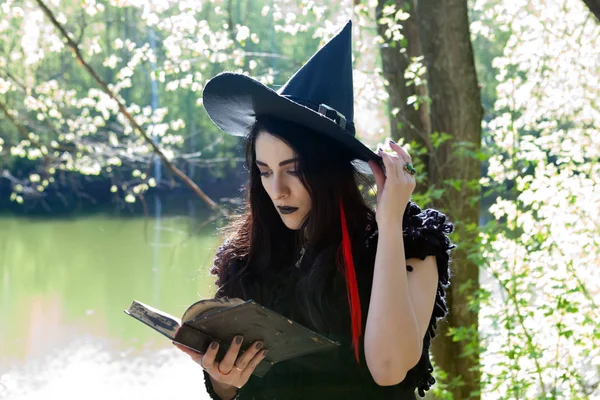 Jovem menina em traje de bruxa com livro — Fotografia de Stock