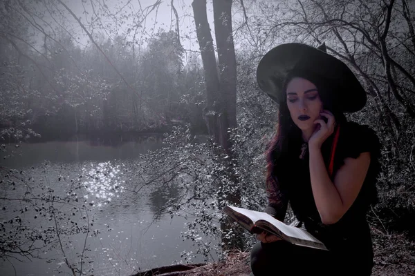 Jovem menina em traje de bruxa com livro — Fotografia de Stock