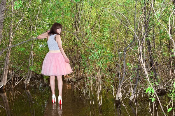 Mädchen im Sommerkleid, umgeben von viel Grün, das am Wasser entlang läuft — Stockfoto