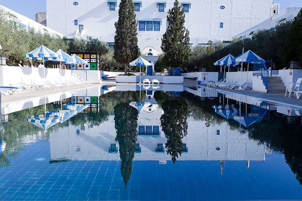 Piscine publique avec chaises longues et parasols bleus — Photo