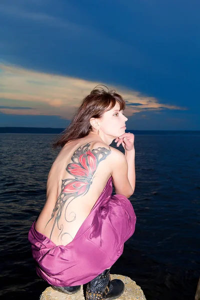 Woman in open dress with butterfly tattoo on her back — Stock Photo, Image