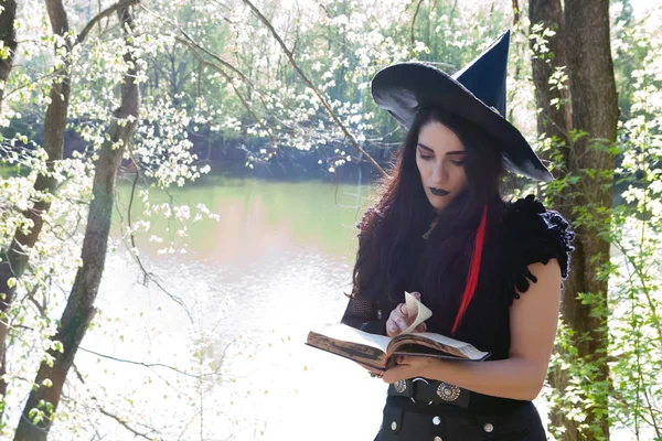 Chica joven en traje de bruja con libro — Foto de Stock