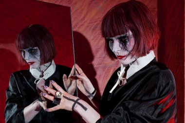 Zombi makyaj kırmızı arka planı yansıtmadaki yakınındaki kadın oyuncu