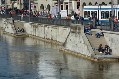 Zürih'te Limmat Nehri yakınında güneşli havanın tadını gençler,