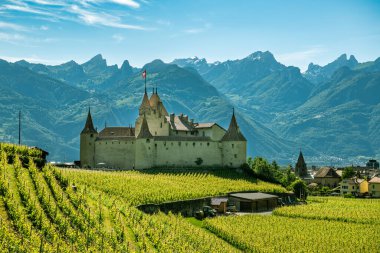 Aigle, Switzerland - June 8, 2019: Castle Aigle in city of Aigle in Switzerland with beautiful Alps in background during sunny day in June 2019
