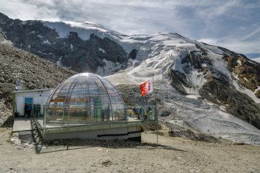 Saas-Grund, Switzerland - August 17, 2019: Tourists enjoying time in mountain bar with nice views on glacier in Hohsaas above the Saas-Grund village, Switzerland during sunny day in August 2019