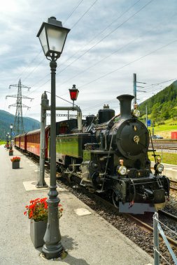 Obergoms, Switzerland - August 16, 2019: Old historic steam train waiting for ride through Furkapass mountain pass on train station in Obergoms, Switzerland during summer 2019