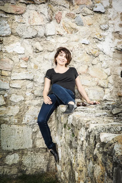 Bella donna sorridente in posa sul muro di pietra, bellezza e fas — Foto Stock