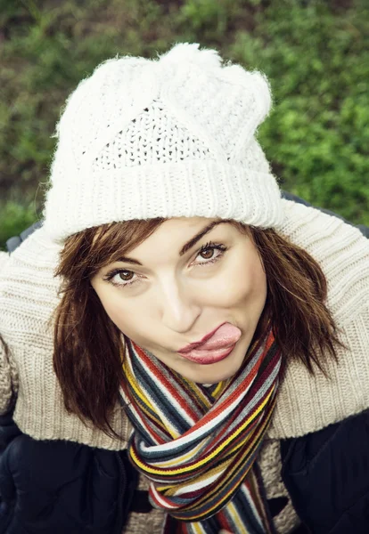 Mujer joven con la lengua hacia fuera está posando en traje al aire libre de otoño — Foto de Stock