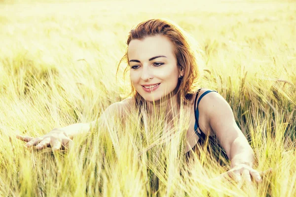 Bella donna nelle pannocchie di grano al tramonto, filtro foto retrò — Foto Stock