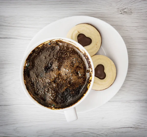 Tasse schwarzen Kaffee mit zwei Marmeladenkeksen in Herzform — Stockfoto