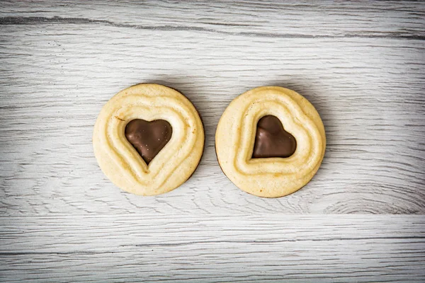 Two jam biscuits in the shape of heart on the wooden background — Stock Photo, Image