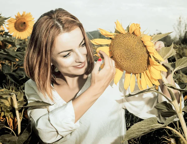 Pretty woman is standing by sunflower, vintage filter — Stock Photo, Image