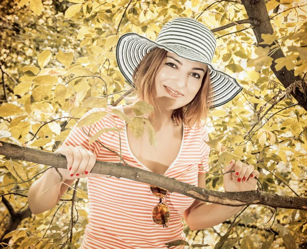 Young woman with stylish sunhat posing on tree, vintage filter — Stock Photo, Image