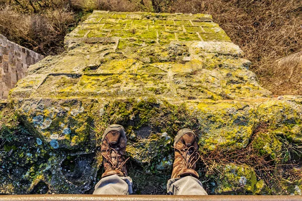 Tourist steht auf hoher Steinmauer, Wanderschuhe Detail — Stockfoto