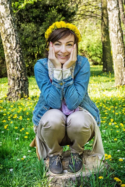 Kvinna med krans av maskrosor i parken — Stockfoto