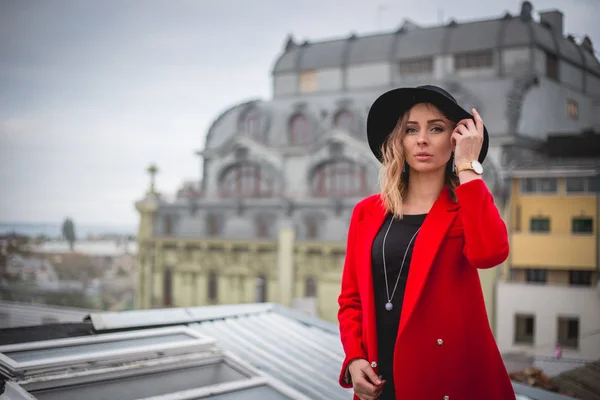 Girl in red and with black hat posing on the roof of old city — Free Stock Photo