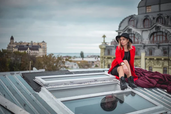 Fata în roșu și cu pălărie neagră pozând pe acoperișul orașului vechi — Fotografie, imagine de stoc