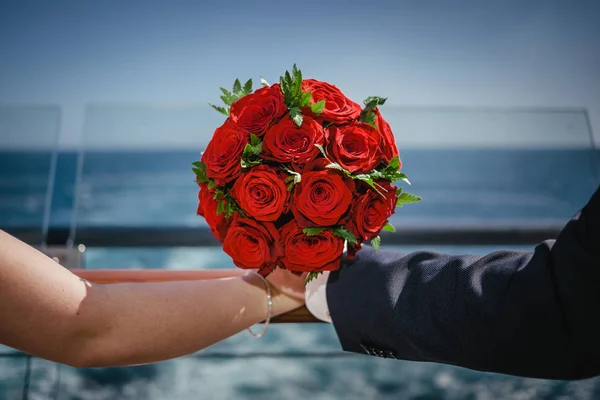 Hermoso ramo de boda rojo de rosas rojas, sosteniendo con las manos — Foto de Stock