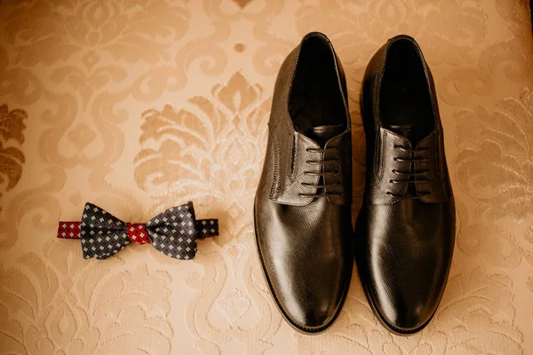 Primer plano de los accesorios modernos del novio. Corbata negra, zapatos de cuero y boutonniere de flores sobre fondo rústico. Set para el estilo formal de llevar aislado sobre fondo blanco — Foto de Stock