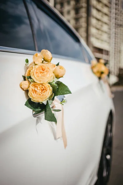 Araba sapında düğün süsleri var. Beyaz bir arabada kurdeleli çiçek süslemesi.