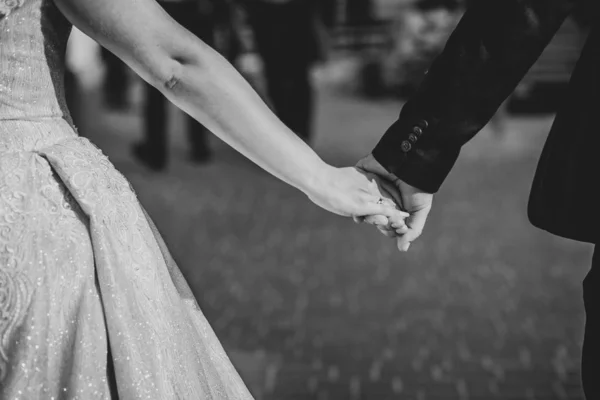 Fecha. Casamento casal está andando de mãos dadas. De vestido branco e casaco azul. Preto e branco — Fotografia de Stock