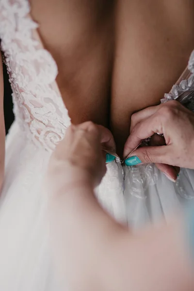 Γυναικεία χέρια Η μητέρα διορθώνει το φόρεμα στην πλάτη μιας νύφης με ένα όμορφο κεντημένο πέπλο και κουμπιά. Κλείστε τα χέρια. Πρωινή προετοιμασία νυφικών λεπτομέρειες νεόνυμφοι. Στιγμές της ημέρας του γάμου, φθορά — Δωρεάν Φωτογραφία