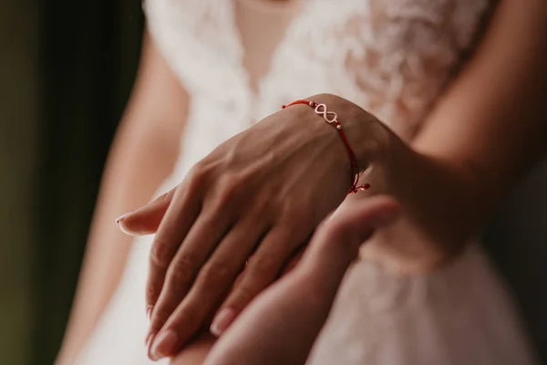 Una mano de pareja de boda se tocan. Manos recién casados con anillos de boda de cerca. Manos de novia con anillos en reposabrazos de cuero negro en asientos de coche — Foto de Stock