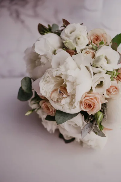 2 arany gyűrű esküvői csokorban, gyönyörű rózsákkal és pionokkal. Esküvő napja. Esküvő előkészítése — Stock Fotó
