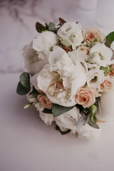 2 anillos de oro en el ramo de bodas con hermosas rosas y piones. Día de la boda. Preparación de boda — Foto de Stock