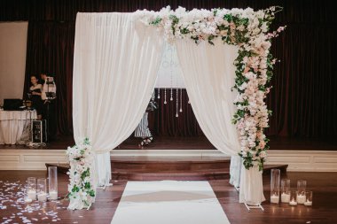Wedding photozone. White photozone with flowers and candles in glass. Wedding flowers decoration in the restaurant