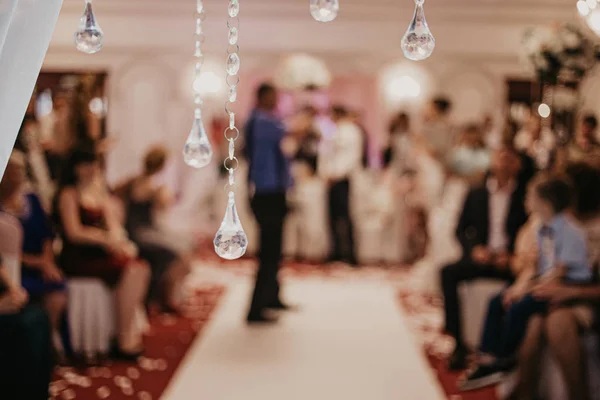 Blur Bokeh oro de cristal hermoso. Arco de boda decoración de primer plano. Colgantes hechos de cristales de cerca. Un montón de invitados y gente con un fondo borroso. Horizontal —  Fotos de Stock