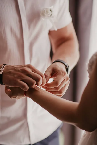 Homme attache un bracelet rouge sur la main de la femme, fil rouge, bijoux, bracelet avec une pierre, accessoires pour femmes. Amour authentique — Photo