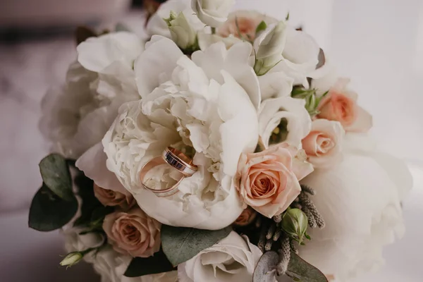 2 anillos de oro en el ramo de bodas con hermosas rosas y piones. Día de la boda. Preparación de boda — Foto de Stock