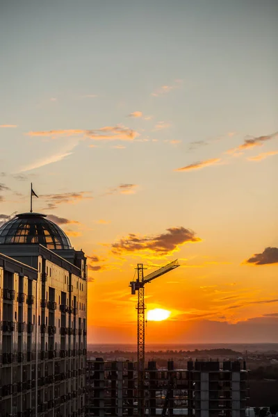 Dunkle Silhouette von Baukran und Gebäude aus Glas auf dem Hintergrund des Sonnenuntergangs. verwendet für Hebezeuge beim Bau von Hochhäusern hinter dem Himmel. odesa, ukraine. kadorr — Stockfoto
