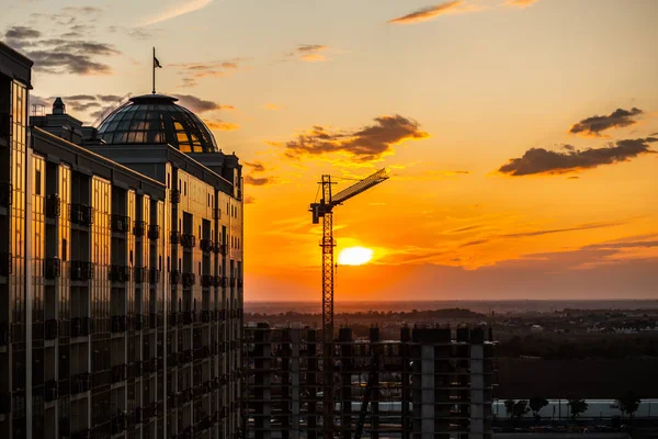 Silhouette of construction crane and building on sunset sky background with red and blue clouds. Dark silhouette of construction crane and building on sunset sky. Odesa, Ukraine. Kadorr — Stock Photo, Image