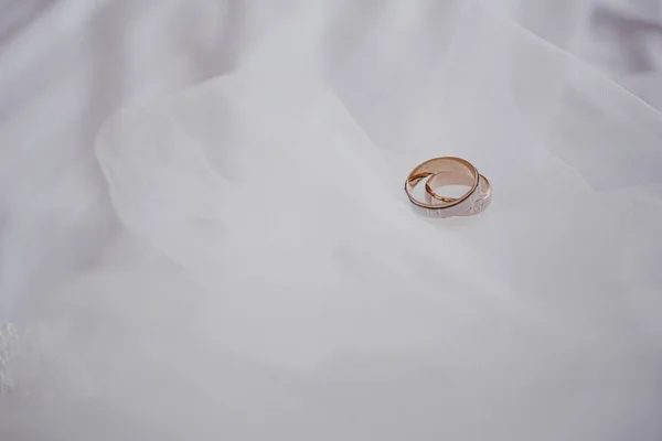 Koncept manželství. Zlaté snubní prsteny na bílém závoji. Detailní záběr. Prostor pro text. Horní pohled — Stock fotografie