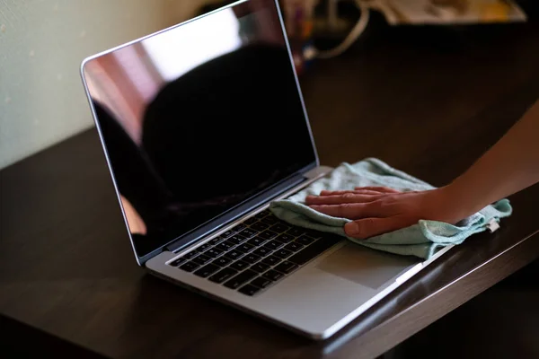 Woman disinfects and cleans laptop keyboard at home, with antibacterial wet wipe to protect from viruses, germs and bacteria during the coronavirus outbreak, covid ncov epidemic. Clean laptop.