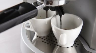 operasyonda kahve makinesi kahve iki beyaz fincan doldurur. Küçük dairesel hareket ile çekim.
