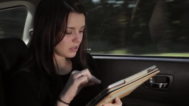 Güzel ciddi kadın arabada tablet üzerinde e-posta okuma — Stok video