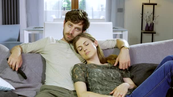 Mann kuschelt verschlafene Freundin auf Sofa beim Fernsehen zu Hause glücklich — Stockvideo
