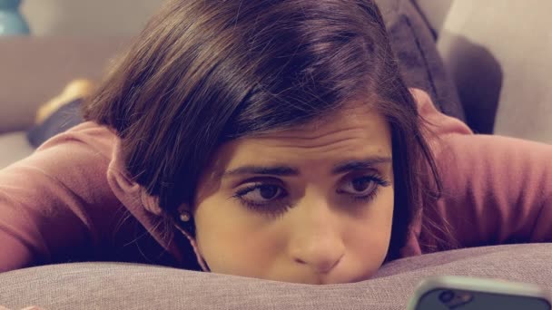 Roztomilá smutná dívka leží na pohovce SMS zprávy s mobilním telefonem — Stock video