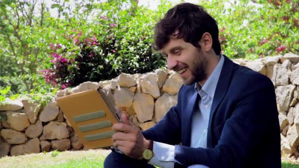 Cool corporate zakenman chatten met tablet in park — Stockvideo