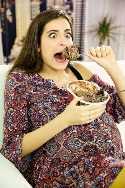 Engraçada bela mulher grávida comendo uma colher grande de sorvete de chocolate — Fotografia de Stock