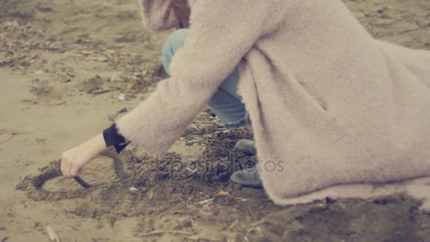 Beautiful woman painting heart on sand hugged by loving boyfriend closeup slow motion retro style — Stock Video