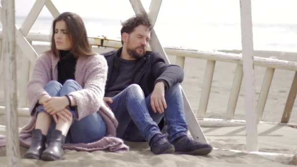Rozzlobený pár boje, sedí na písku na pláži — Stock video