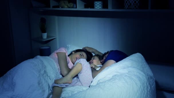 Rodziny w łóżku w nocy, grając z córeczką — Wideo stockowe