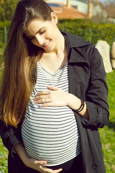 Vacker ung gravid kvinna som håller magen leende — Stockfoto
