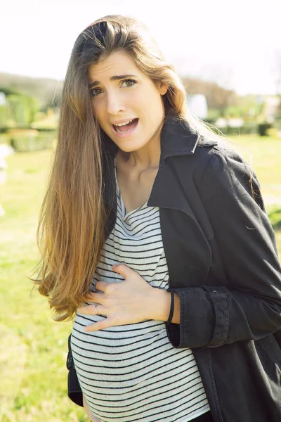 Mulher grávida sentindo contrações no parque assustado — Fotografia de Stock